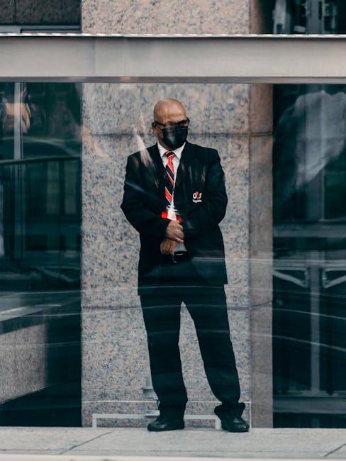 Bald corporate security guard in black suit and tie stands in an urban environment, providing security.
